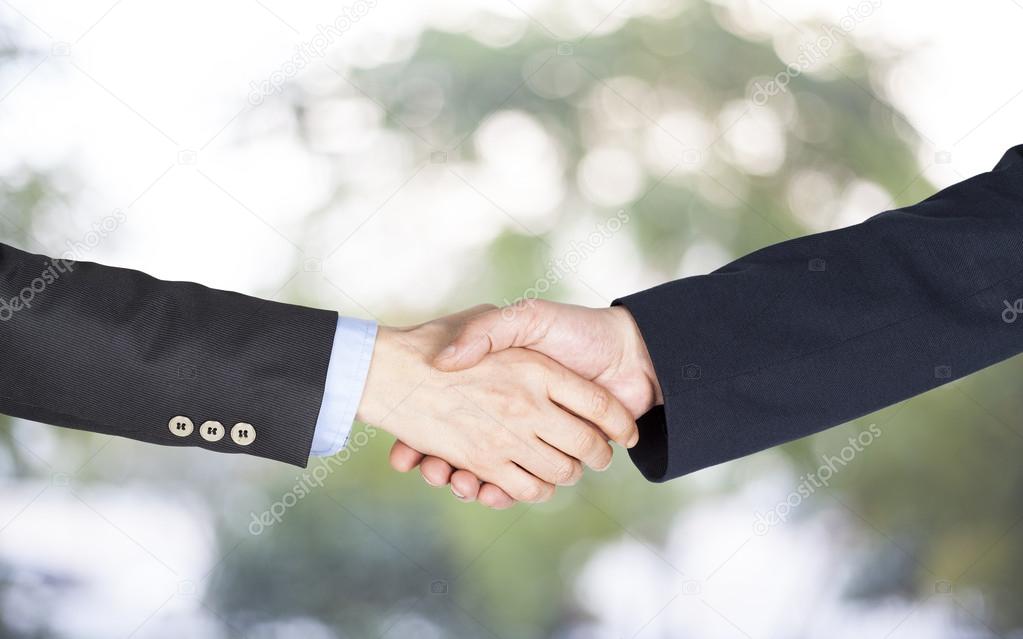 Hand shake between a businessman and a businesswoman on green background