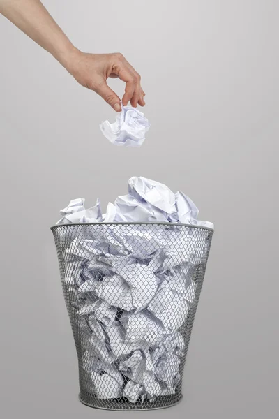 Mujer mano lanzando papel arrugado en un cubo de basura de plata —  Fotos de Stock