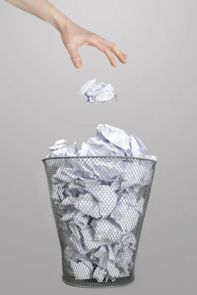 La mano de una mujer tirando papel arrugado en un cubo de basura de plata — Foto de Stock