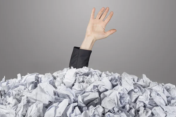 Die Hand streckt sich aus einem großen Haufen zerknüllter Papiere — Stockfoto