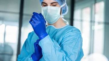 Koruyucu mavi eldiven koyarak doktor