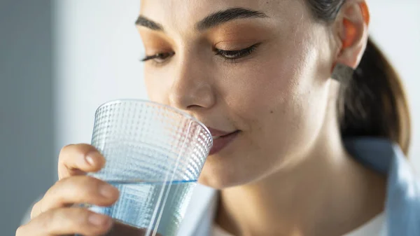 若い女性がコップ一杯の水を飲み — ストック写真