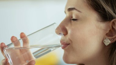 Genç bayan bir bardak su içiyor.