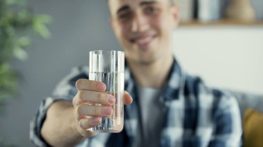 Genç adam bir bardak su içiyor.