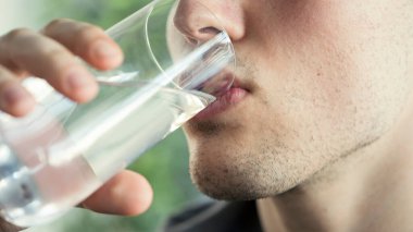 Genç adam bir bardak su içiyor.