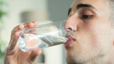 Genç adam bir bardak su içiyor.