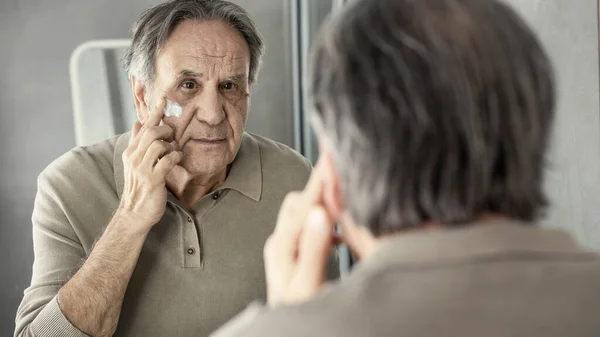 Viejo Aplicando Crema Cara — Foto de Stock