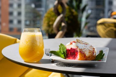 Kiraz ya da kırmızı böğürtlenli geleneksel Avusturya çöreği ve bir bardak portakal suyuyla pudra şekeri. Kafe için menü. Parlak arkaplan.