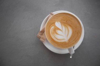 Gri arka planda izole edilmiş süt köpüklü latte sanat dokusuyla beyaz kahve. Genel görünüm, kopyalama alanı. Kafe menüsü reklamı. Kahve dükkanı menüsü.