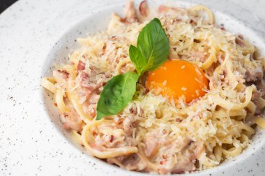 Carbonara usulü makarna. Pastırmalı spagetti, parmesan, krema sosu ve yumurta sarısı. Makro yakın plan beyaz bir tabakta izole edilmiş. Akdeniz gurme yemekleri.