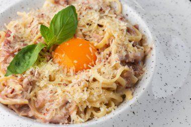 Carbonara usulü makarna. Pastırmalı spagetti, parmesan, krema sosu ve yumurta sarısı. Makro yakın plan beyaz bir tabakta izole edilmiş. Akdeniz gurme yemekleri.