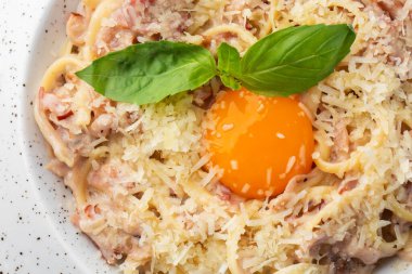 Carbonara usulü makarna. Pastırmalı spagetti, parmesan, krema sosu ve yumurta sarısı. Makro yakın plan beyaz bir tabakta izole edilmiş. Akdeniz gurme yemekleri.