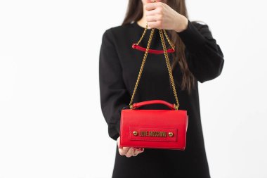 Moschino 'nun kırmızı deri çantasıyla poz veren bir manken. Ofis için modaya uygun çanta, iş seyahatleri veya beyaz arka planda izole edilmiş sıradan durumlar.