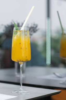 Sarı limon ve tutkulu meyve kokteyli bardakta. Parlak bir zemin üzerinde kurumuş ananas ve nane ile süslenmiş..