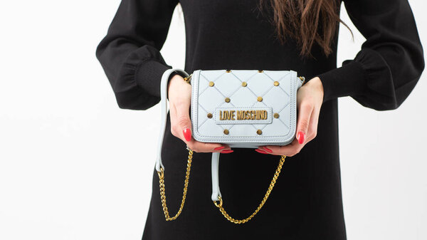 МИЛАН, ИТАЛИЯ - 21 февраля: Модель позирует с голубой кожаной сумкой Moschino. Модный кошелек для офиса, деловых поездок или случайных мероприятий, изолированных на белом фоне.