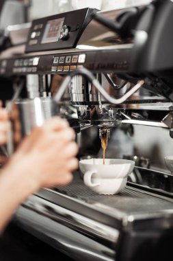 Profesyonel makineden fincana kahve dökülüyor. Barista espresso yapıyor, filtre tutacağı kullanıyor. Taze kahve akıyor. Sabahları kavrulmuş sade kahve içmek..