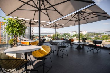 Parlak bahçe mobilyaları ve ahşap zemin ve tuğla duvarlı rahat terasta bitkiler. Bir restoranın yaz terası.