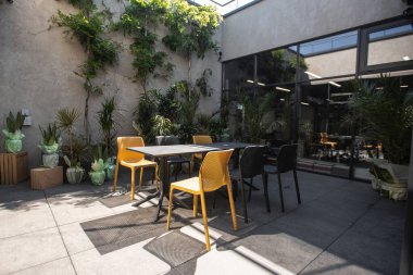 Parlak bahçe mobilyaları ve ahşap zemin ve tuğla duvarlı rahat terasta bitkiler. Bir restoranın yaz terası.