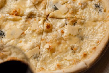 Dört peynirli pizza quattro formaggi ve koyu arkaplanda bir bardak şarap..