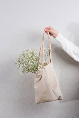 Beyaz çingene çiçekleriyle dolu bir çanta. Parlak düzlükte bir kadının elinde. Çingene Bebek nefes çiçekleri, ışık, havadar küçük beyaz çiçekler..