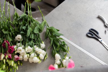 Masada kağıt ile güzel bir buketi saran bayan bir çiçekçi, masaüstü manzaralı. Yüksek kalite fotoğraf