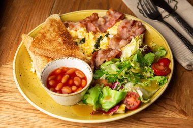 Sebzeli haşlanmış yumurta, jambon, domates, kırmızı fasulye ve ahşap arka planda izole edilmiş ekşi ekmek. Ev yapımı yemek. Lezzetli bir kahvaltı. Seçici odak.