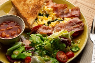 Sebzeli haşlanmış yumurta, jambon, domates, kırmızı fasulye ve ahşap arka planda izole edilmiş ekşi ekmek. Ev yapımı yemek. Lezzetli bir kahvaltı. Seçici odak.