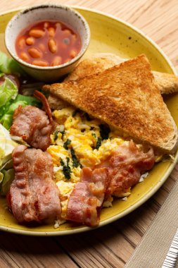 Sebzeli haşlanmış yumurta, jambon, domates, kırmızı fasulye ve ahşap arka planda izole edilmiş ekşi ekmek. Ev yapımı yemek. Lezzetli bir kahvaltı. Seçici odak.