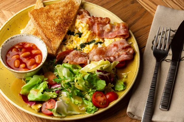 Sebzeli haşlanmış yumurta, jambon, domates, kırmızı fasulye ve ahşap arka planda izole edilmiş ekşi ekmek. Ev yapımı yemek. Lezzetli bir kahvaltı. Seçici odak.