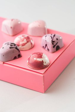 Beyaz arka planda izole edilmiş pembe kutuda lüks el yapımı çikolata şekeri. Özel el yapımı bir bonbon. Pasta dükkanı için ürün reklamcılığı konsepti.