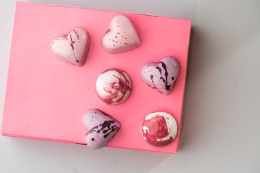 Beyaz arka planda izole edilmiş pembe kutuda lüks el yapımı çikolata şekeri. Özel el yapımı bir bonbon. Pasta dükkanı için ürün reklamcılığı konsepti.
