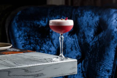 Pembe Yonca Kulübü Kokteylleri Coupe Glass 'ta Köpük tabakası ve karanlığa gömülmüş çiçek garnitürleriyle.