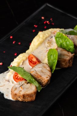 Beyaz tabakta garnitür olarak fırında et ve patates püresi. Makro yakın plan siyah arka plan. Lezzetli yemek, restoran menüsü konsepti