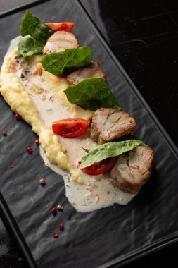 Beyaz tabakta garnitür olarak fırında et ve patates püresi. Makro yakın plan siyah arka plan. Lezzetli yemek, restoran menüsü konsepti