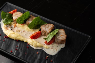 Beyaz tabakta garnitür olarak fırında et ve patates püresi. Makro yakın plan siyah arka plan. Lezzetli yemek, restoran menüsü konsepti