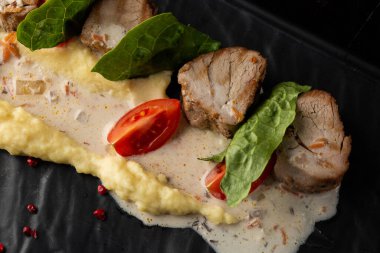 Beyaz tabakta garnitür olarak fırında et ve patates püresi. Makro yakın plan siyah arka plan. Lezzetli yemek, restoran menüsü konsepti