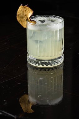 Gece kulübü restoranındaki cam masada klasik kokteyl camı. Alkol kokteyli, garnitür ve elma cipsi. Yakın plan. Modern alkolik