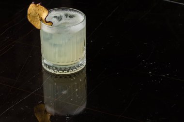 Gece kulübü restoranındaki cam masada klasik kokteyl camı. Alkol kokteyli, garnitür ve elma cipsi. Yakın plan. Modern alkolik