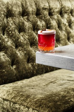 Bulanık arka plandaki çelik tezgahın üzerinde duran küçük kozalaklı ve portakal aromalı bir New York kokteyli..