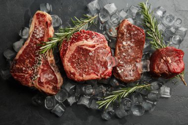 Koyu taşlı tahtada çiğ domuz eti ve baharat. Üst Manzara. Çiğ et, biber, otlar, sarımsak. Mesaj için yer var. Biftek pişirmeye hazır. İçindekiler.