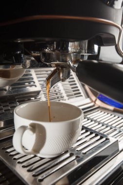 Profesyonel makineden fincana kahve dökülüyor. Barista espresso yapıyor, filtre tutacağı kullanıyor. Taze kahve akıyor. Sabahları kavrulmuş sade kahve içmek..