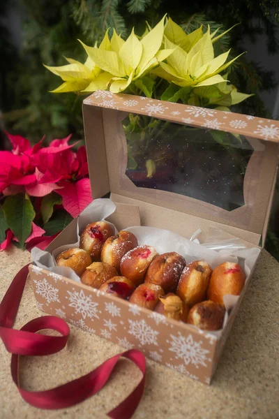 German donuts - berliner with filling and icing sugar in a box on a brown stone table. On Christmas decoration background