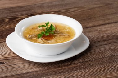 Erişteli tavuk çorbası, tavuk eti, dereotlu ve maydanozlu beyaz kâse. Ahşap arka planda izole edilmiş. Sağlıklı yemek menüsü