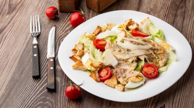 Izgara tavuk göğsü, marul, kızarmış ekmek, yumurta, vişneli domates, parmesan peyniri ve soslu Sezar salatası..