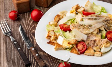 Izgara tavuk göğsü, marul, kızarmış ekmek, yumurta, vişneli domates, parmesan peyniri ve soslu Sezar salatası..