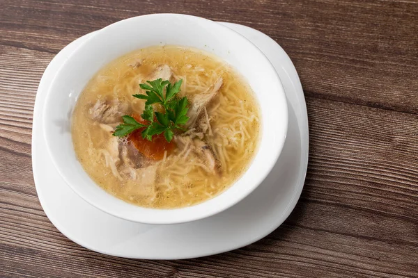 Erişteli tavuk çorbası, tavuk eti, dereotlu ve maydanozlu beyaz kâse. Ahşap arka planda izole edilmiş. Sağlıklı yemek menüsü