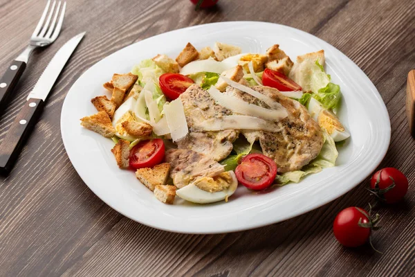 Izgara tavuk göğsü, marul, kızarmış ekmek, yumurta, vişneli domates, parmesan peyniri ve soslu Sezar salatası..