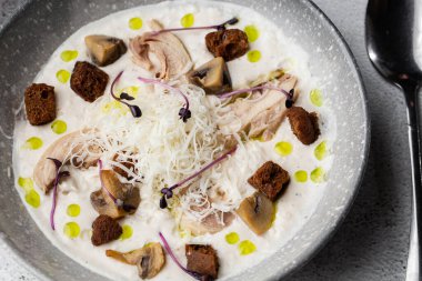 Bir kase mantar kremalı çorba, kızarmış şampiyonlar ve gri mermer arka planda tavuk. Kış, sonbahar sıcak çorba konsepti.