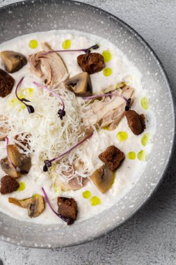 Bir kase mantar kremalı çorba, kızarmış şampiyonlar ve gri mermer arka planda tavuk. Kış, sonbahar sıcak çorba konsepti.