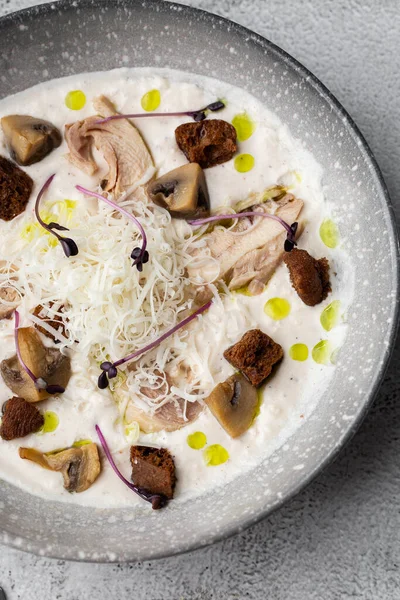 Bir kase mantar kremalı çorba, kızarmış şampiyonlar ve gri mermer arka planda tavuk. Kış, sonbahar sıcak çorba konsepti.